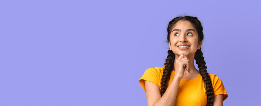 A girl with long braids and a cheerful expression is thoughtfully smiling while standing against a soft purple background. She appears to be pondering or considering something happy.