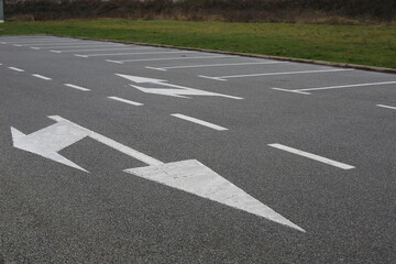 Empty parking lot with white directional arrows and marked parking spaces on a clean asphalt surface © Maryna
