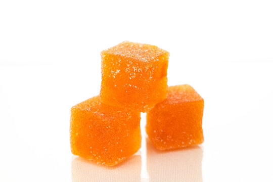 Three orange cubes of marmalade candy on a white background