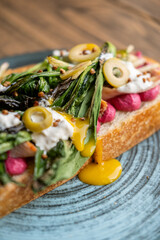 Gourmet toast. Nutrition food. Artisan bread with green leaves meat on plate. Portion meal with dripping bright sauce olive mustard.
