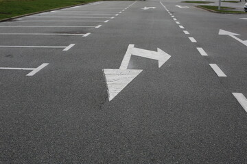 Empty parking lot with white directional arrows and marked parking spaces on a clean asphalt surface © Maryna