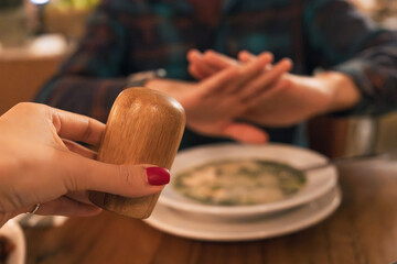 Hands holding a pepper mill offering seasoning while another person rejects it with a stopping...