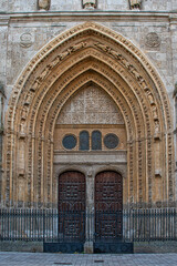 Flamboyant Gothic style entrance with pointed and splayed arch with reliefs and sculptures and wooden door with mullion known as the Gate of the Kings of the Cathedral of San Antol&iacute;n in Palencia, Spai