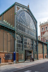 19th-century iron architecture building at one of the entrances to the market hall in the city of Palencia, Spain. The sign next to the entrance has the word written in Spanish, "mercado de abastos" (