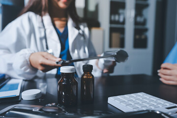Female doctor holding a medicine bottle is checking the quality of medicine for any side effects the patient or not and recording patient information at the hospital. medical and health care concept