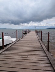 Fototapeta premium Naroch, Belarus, July 11, 2025. A large wooden pier on a lake before a thunderstorm in summer.