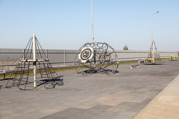 Modern playground equipment with rope net and geometric climbing structure. Outdoor recreation, urban design, children play area. Real photo