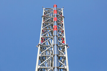 Boiler house stack with red and white markings against blue sky. Heating infrastructure, industrial exhaust gases, energy systems. Real photo
