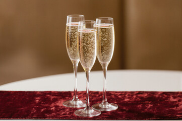 Three champagne flutes filled with sparkling wine, placed on a red velvet runner, symbolizing celebration and sophistication.