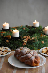 Traditional Czech and Slovak Christmas sweet plaited bread called vanocka (in Slovak vianocka), Christmas cookies and a Christmas advent wreath with four burning candles on wooden table.