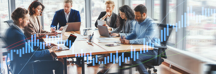 In a bright and airy modern office, a group of business professionals work on their laptops around...