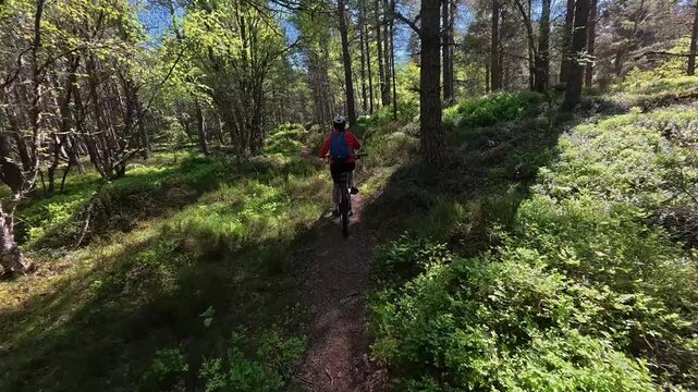 nice senior woman riding her electric mountain bike  in the highlands of Cairn Gorms National Park , Scotland, UK