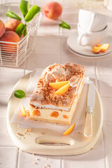 Sweet and homemade peach cheesecake served on white kitchen.