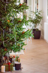 Fototapeta premium A cozy indoor scene featuring a festive Christmas tree adorned with sparkling decorations and gifts