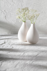 Stone background and white vase with flowers.