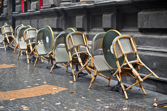 Row of empty chairs are lined up on a sidewalk