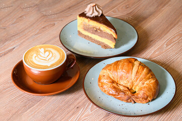 Coffee latte art, croissant, and layered cake