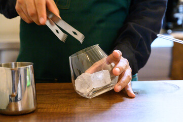Barista preparing cold drink with ice and tongs
