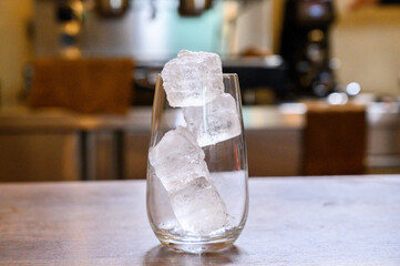 Ice cubes filling clear glass on wooden counter