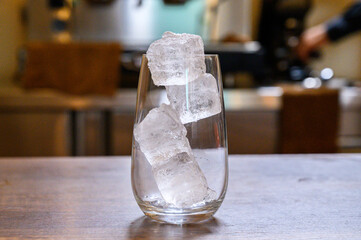 Glass of ice cubes on wooden counter