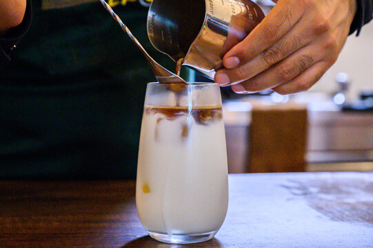 Barista preparing iced latte coffee drink with milk - Powered by Adobe