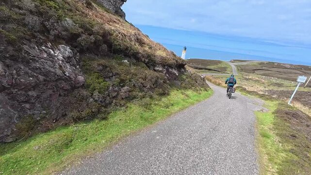 active senior man riding her electric mountain bike on the moor landscape of Rua Reidh point near Gairloch in Scotland, UK