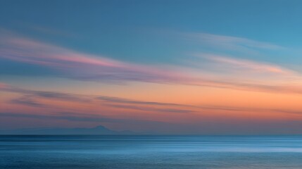 Obraz premium Serene ocean landscape features layered colorful clouds above distant coastal silhouette at twilight
