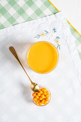 A refreshing orange drink sits beside a small bowl of cheerful yellow berries, inviting taste