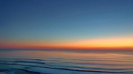 Obraz premium Horizon line perfectly divides richly colored twilight sky above serene ocean waves