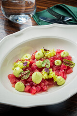 Colorful dish features juicy watermelon cubes topped with a vibrant green sauce and herbs