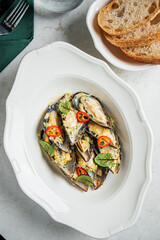 A delightful dish of mussels garnished with herbs and chili, enjoyed in a charming dining setting