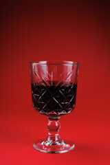 Ornate vintage wine glass filled with red wine against a vivid red backdrop showcasing luxury and elegance