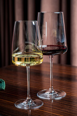 Two stylish glasses hold shimmering white wine and deep red wine, capturing a moment of elegance
