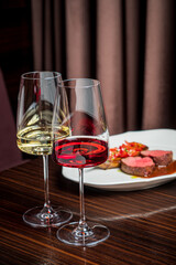 Two glasses filled with red and white wine sit next to a beautifully plated gourmet dish