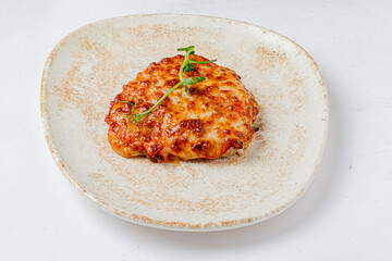 Golden brown melted cheese tops a flavorful dish, garnished with fresh herbs on the plate