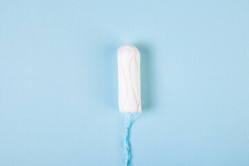 Hygienic cotton tampon on blue background. Feminine menstrual hygiene products. Womens health concept. Copy space.
