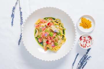 A colorful bowl of creamy pasta with fresh veggies and herbs offers a wholesome taste