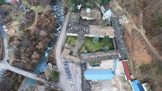 Drone video of the Troyan Monastery in March, showing the rooftops, the river, nearby nature and the winding road with cars. Smooth camera movement highlights the landscape, BG, EU, 02 Mach 2019