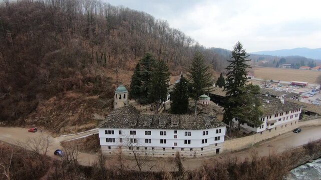 Drone video of the Troyan Monastery in March, showing the rooftops, the river, nearby nature and the winding road with cars. Smooth camera movement highlights the landscape, BG, EU, 02 Mach 2019