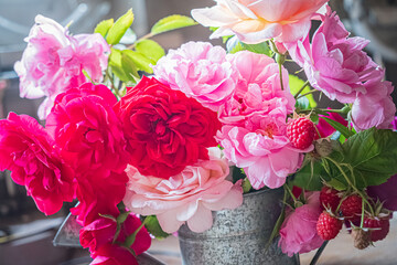 Vibrant roses in shades of pink and red mingle with fresh raspberries in a charming setting