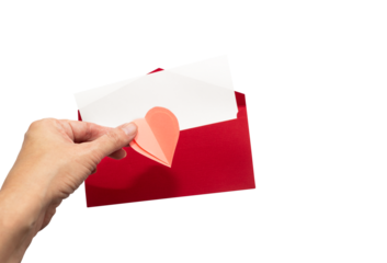 Red envelope with white card and pink heart decoration in a hand, open, isolated on white background, romantic and festive
