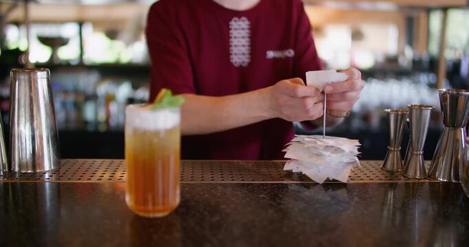 Cafe management. Bartender workflow. Worker adding paper receipt to pile on metal spike holder counter. Busy cocktail bar lunchtime rush.