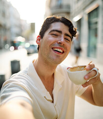 Portrait of a smiling young man guy with a coffee cup in a coffee shop or a restaurant in the city,...