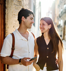 Couple enjoys a sunny day walking together in a charming urban area during late afternoon or tourists visiting a destination  looking at phone map app