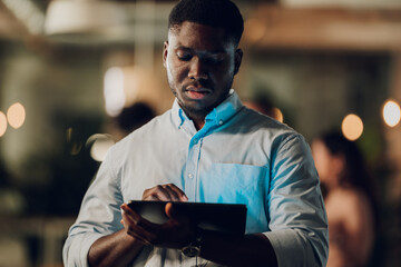 Black businessman focused, working late on digital tablet