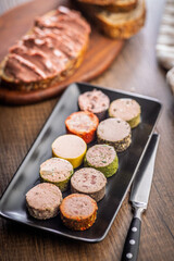 Liver pate with cranberries on plate on wooden table.