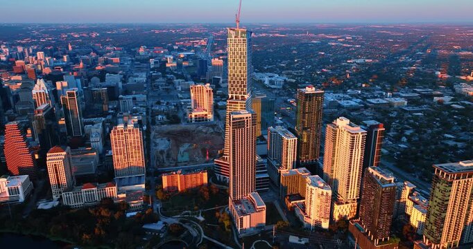 High-rises lit by the setting sun surround the empty space in the cityscape prepared for the construction. Panorama of Austin, Texas, USA.