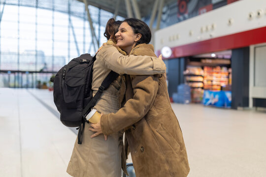 Women embracing emotional farewell at airport terminal - Powered by Adobe