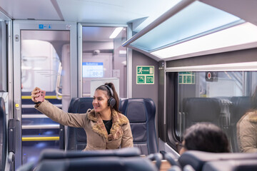 Young woman taking selfie using smartphone on train
