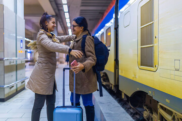 Young women embracing during train station departure